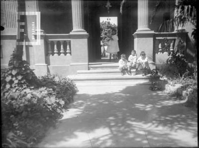 Niños sentados en escalones entrada con columnas