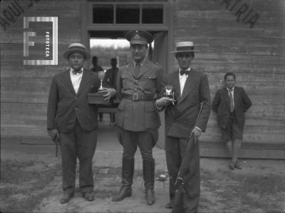 En Tiro Federal, 1934, militar en el centro y dos tiradores con trofeo