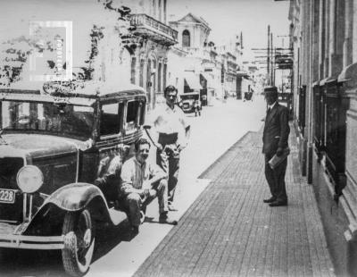Carlos N. y César C. Bustos junto a automóvil en calle Nación entre Sarmiento y Francia