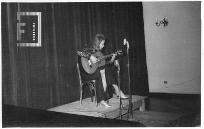 Dama tocando guitarra en sala auditorio