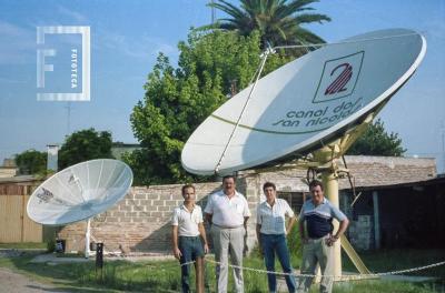 Personal y directivo de Canal 2 junto a parábolas de recepción satelital