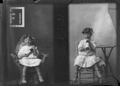 Retrato de una niña de 2 años en ropa de vestir sentada en la silla